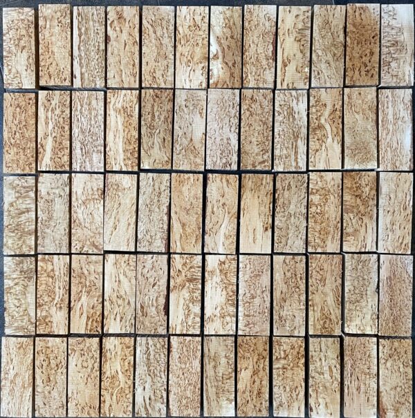 An array of curly birch wood blocks neatly arranged in a grid pattern, each piece displaying a unique pattern of swirled and wavy grain typical of the Masur birch variety, with variations in color and texture across each block.