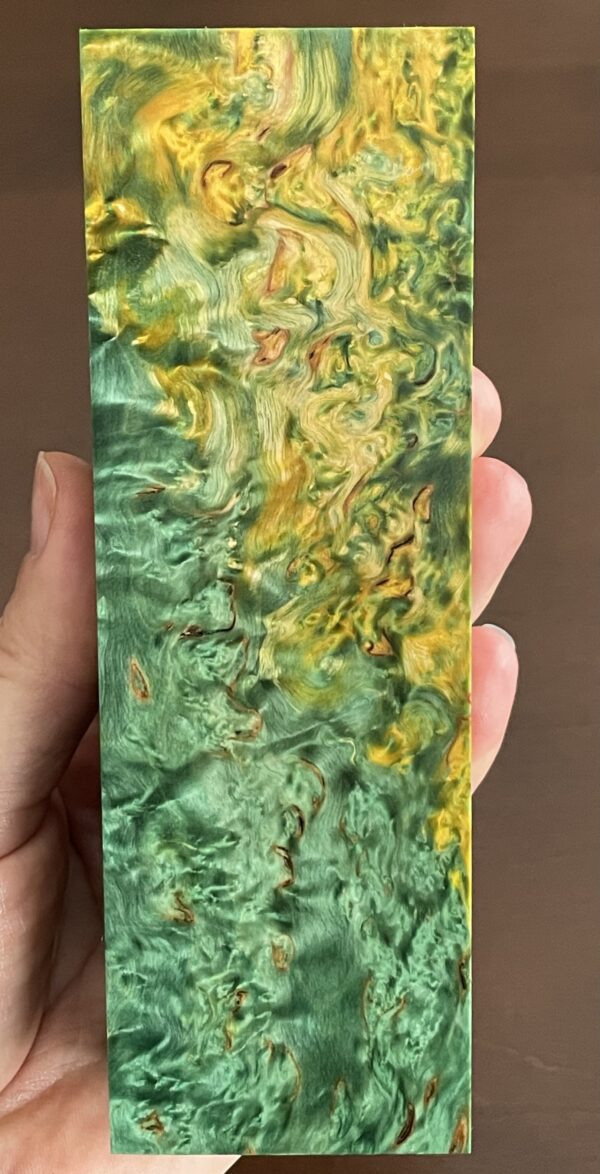 A green and golden colored block of curly birch, also known as masur birch, showcasing its distinctive marble-like swirls.